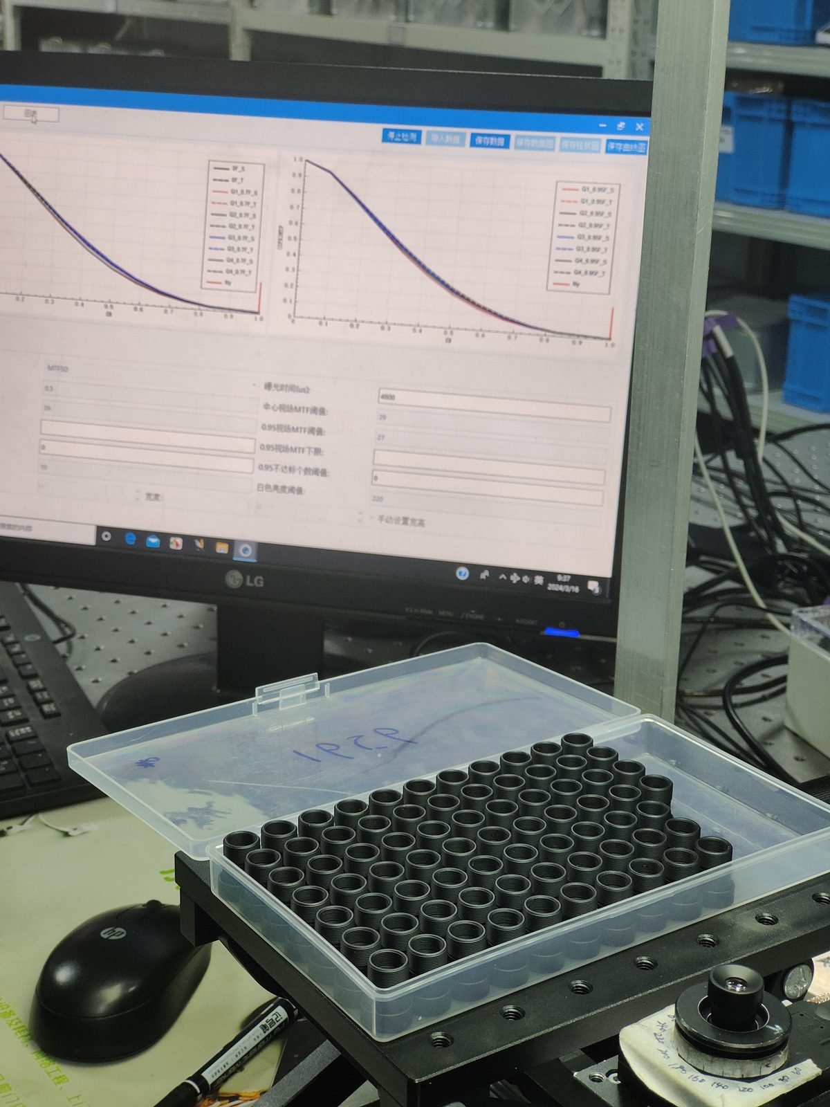 Tray of identical Lensmind lens barrels on an MTF bench with measured curves on the monitor