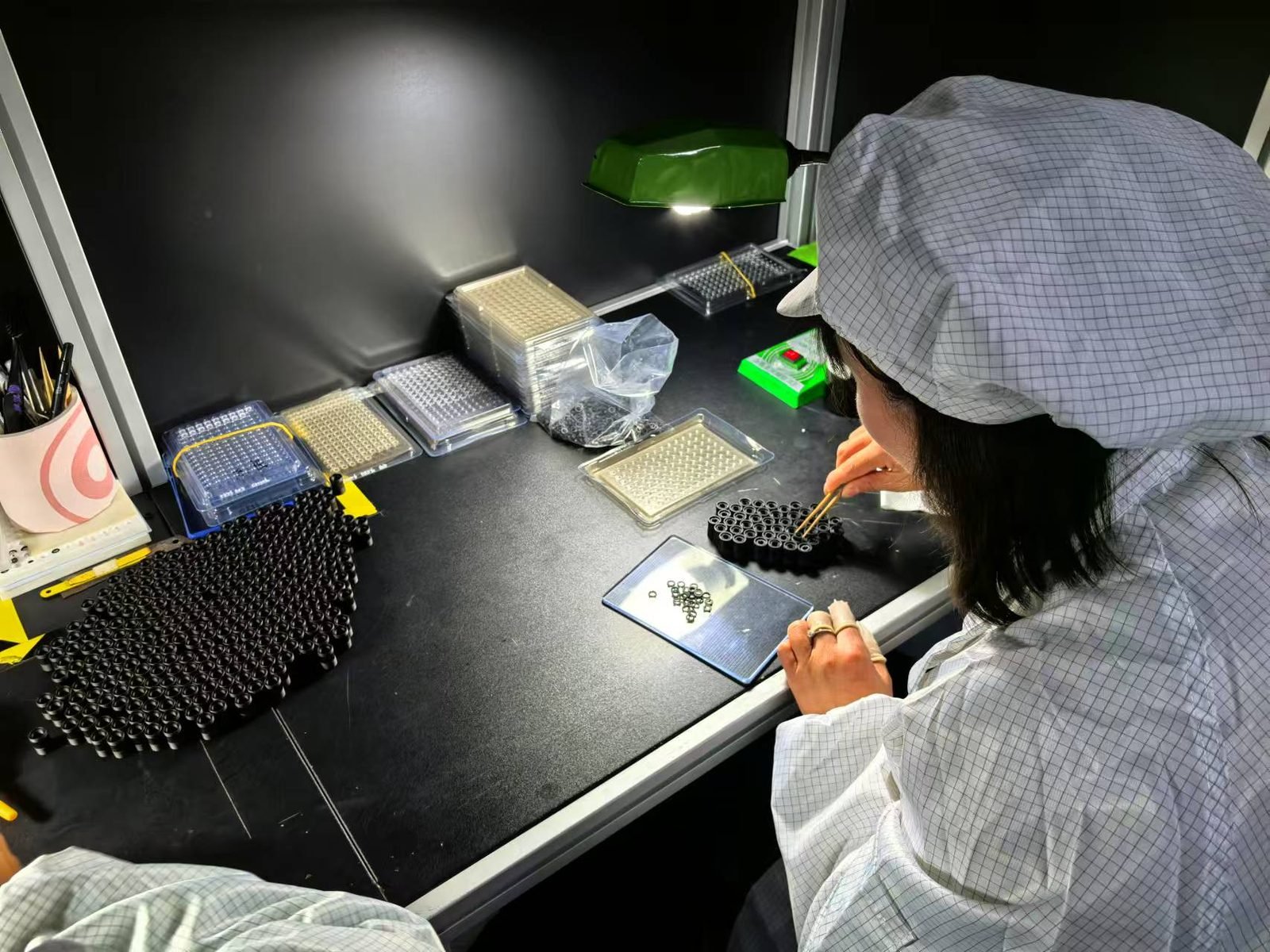 Cleanroom technician assembling compact Lensmind lens barrels and micro-elements at the bench