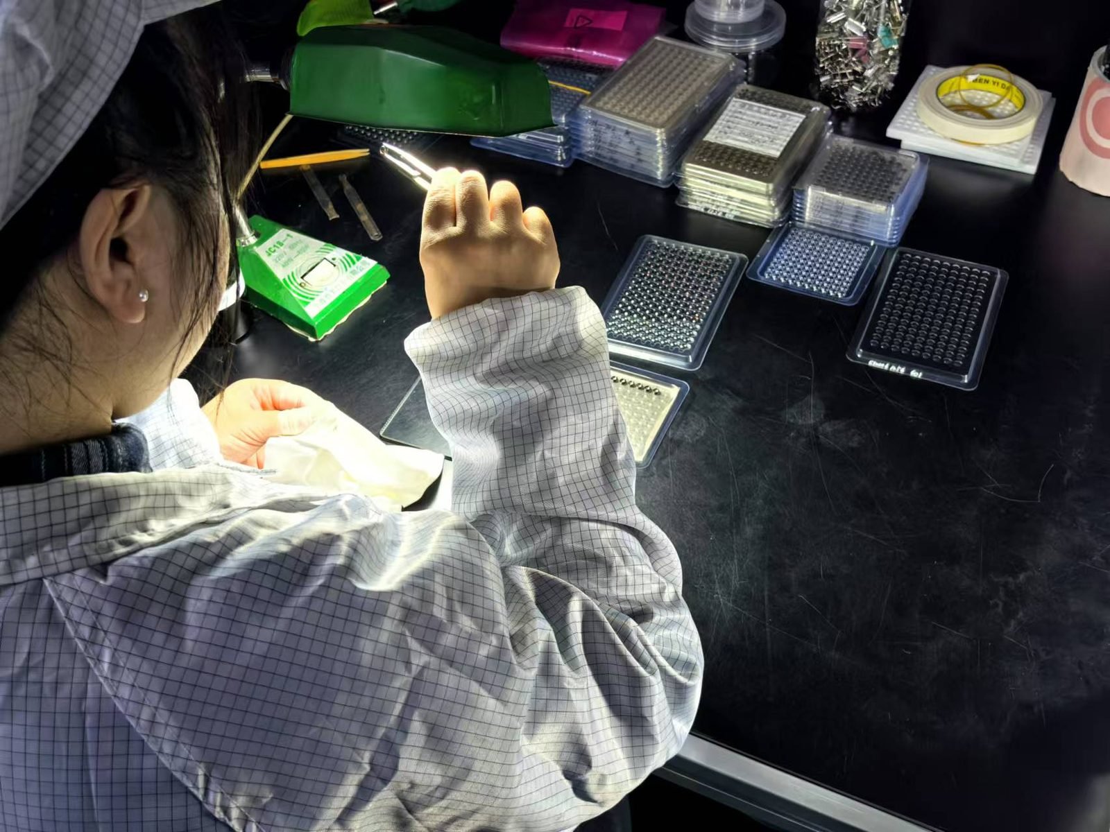 Technician assembling trays of miniature Lensmind optical elements at a clean bench